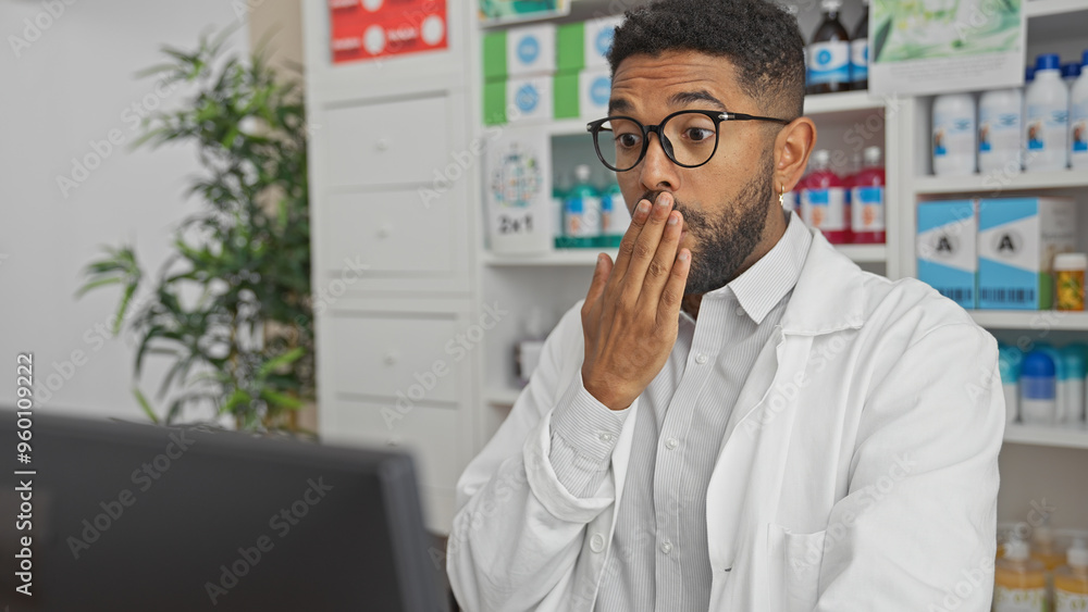 A surprised young african american man with a beard wearing glasses and a white coat in a pharmacy interior A surprised young african american man with a beard wearing glasses and a white coat in a pharmacy interior