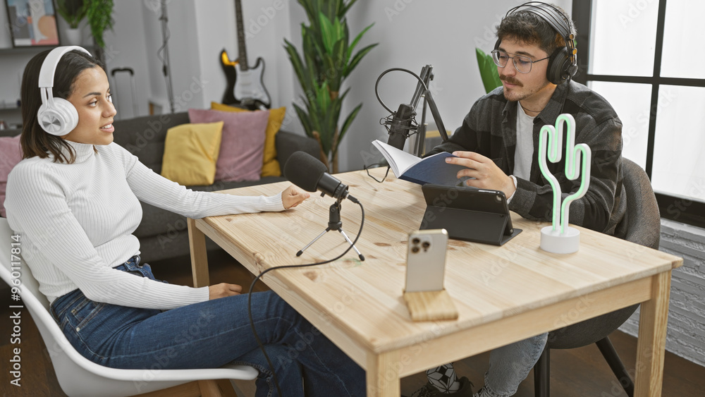 A man and woman engage in a podcasting session indoors, with microphones, headphones, and a cozy studio setup. A man and woman engage in a podcasting session indoors, with microphones, headphones, and a cozy studio setup.