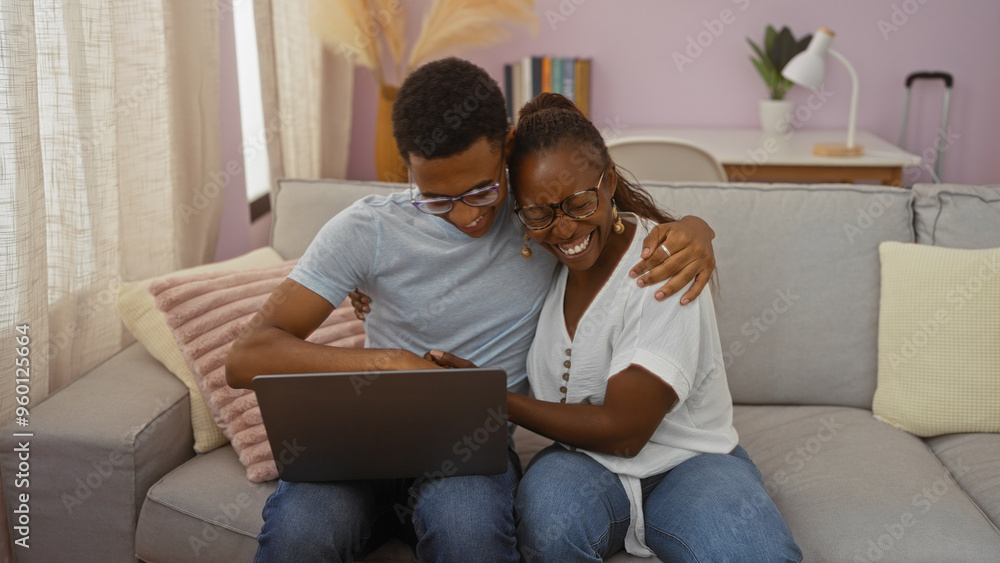 Mother and son embracing while using a laptop on a sofa in a cozy living room, showing love and togetherness in an indoor home setting Mother and son embracing while using a laptop on a sofa in a cozy living room, showing love and togetherness in an indoor home setting