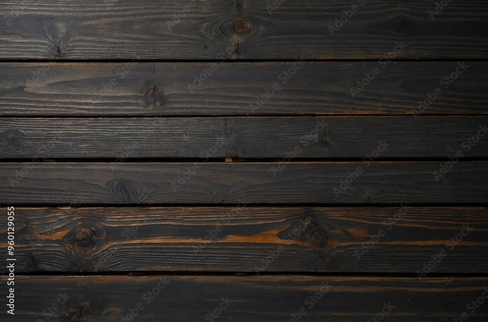 Obraz premium A close-up view of a dark table made of wood planks arranged horizontally. The surface of the table is aged and textured, with natural wood grain patterns. Grunge wooden background.