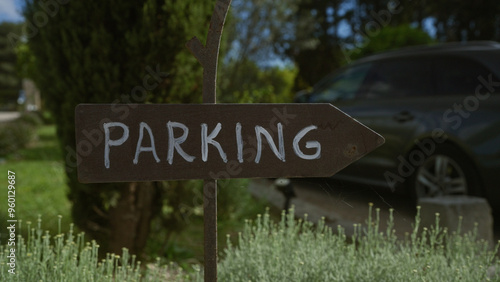 Rustic parking sign in an outdoor garden with blurred car and greenery in the background photo