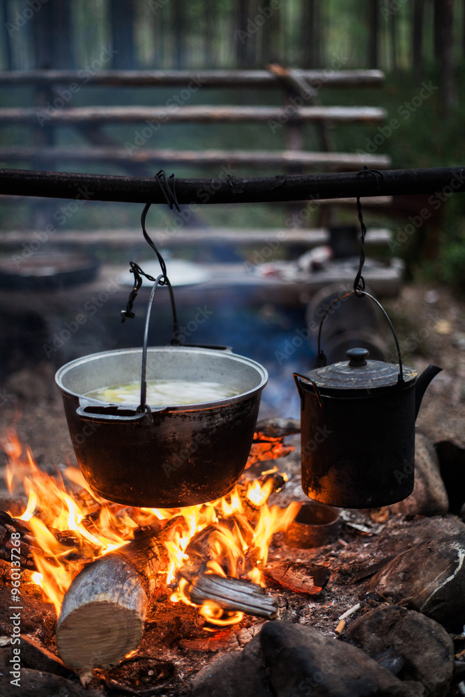 A pot of boiling water is hanging over a fire A pot of boiling water is hanging over a fire