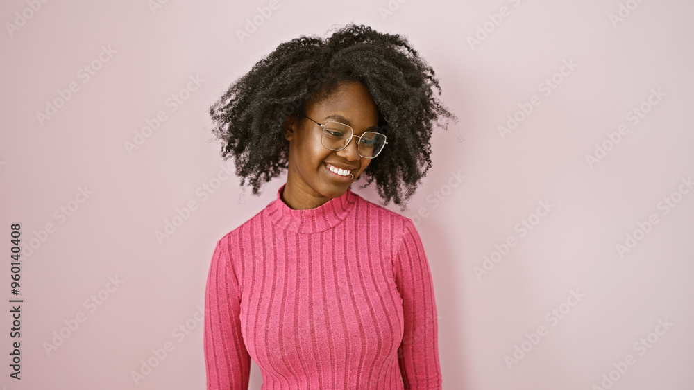Smiling african american woman in pink sweater and glasses posing for a portrait in a pink-hued room. Smiling african american woman in pink sweater and glasses posing for a portrait in a pink-hued room.