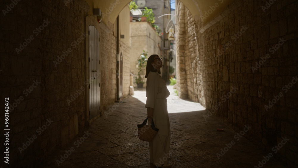 Young hispanic woman exploring the narrow stone streets of bari old town in puglia, italy, on a sunny day. Young hispanic woman exploring the narrow stone streets of bari old town in puglia, italy, on a sunny day.