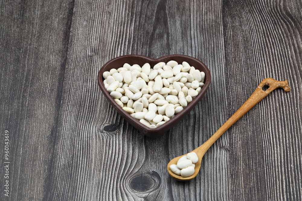 white kidney beans in a heart shaped bowl a on wooden background.Top view. white kidney beans in a heart shaped bowl a on wooden background.Top view.