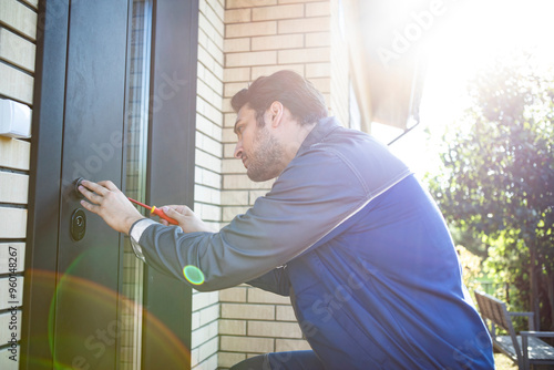 Handsome repairman fixing the door on the backyard 