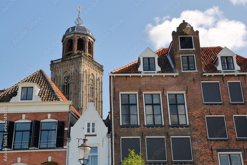 Traditional historic medieval houses, located on the banks of the river Ijssel, in the historical city center of Deventer, Overijssel, Netherlands, with the bell tower of Lebuinus church Traditional historic medieval houses, located on the banks of the river Ijssel, in the historical city center of Deventer, Overijssel, Netherlands, with the bell tower of Lebuinus church