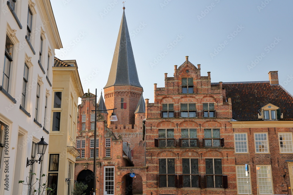 Obraz premium Traditional historic medieval houses in the old picturesque town of Zutphen, Gelderland, Netherlands, with Drogenapstoren tower (ancient gateway to the city) in the background