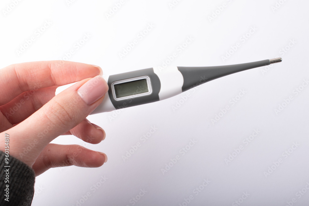 Womans hand holding a digital thermometer. Measuring body temperature. Health check. Health care concept. High quality photo Womans hand holding a digital thermometer. Measuring body temperature. Health check. Health care concept. High quality photo