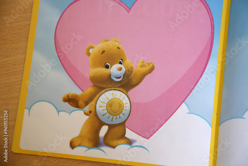 
Children's book with the character of Funshire bear. Yellow care bear with heart background with copy space. Template. Card. Mockup. Cartoon for kids.