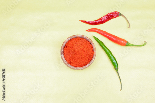 spicy red chilli powder with super chilli background. Top View of Red chilly powder in marbel bowl with red chilly isolated on yellow background. Indian spices, paprika powder or red chilli powder.