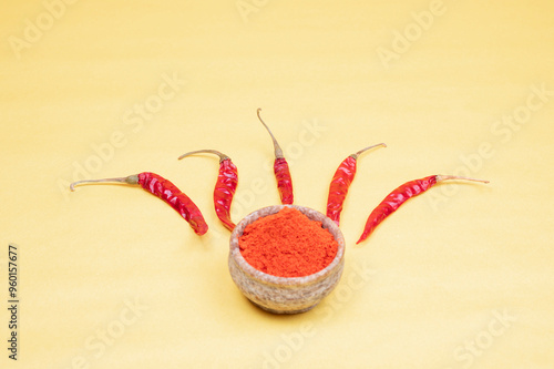 spicy red chilli powder with super chilli background. Top View of Red chilly powder in marbel bowl with red chilly isolated on yellow background. Indian spices, paprika powder or red chilli powder.