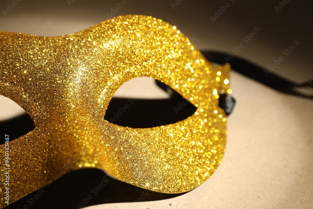 Naklejka premium Beautiful golden carnival mask on beige background, closeup