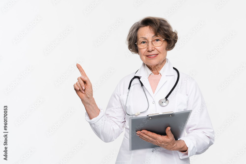 Portrait of smiling mature senior woman, female doctor wearing white coat uniform, stethoscope, looking at camera holding clipboard isolated on white background. Health care concept Portrait of smiling mature senior woman, female doctor wearing white coat uniform, stethoscope, looking at camera holding clipboard isolated on white background. Health care concept