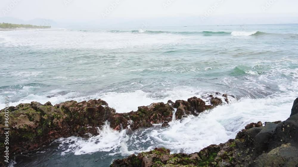 sea wave crashing againts mossy rocks in karang hawu beach, indonesia. beautiful and calm beach atmosphere sea wave crashing againts mossy rocks in karang hawu beach, indonesia. beautiful and calm beach atmosphere