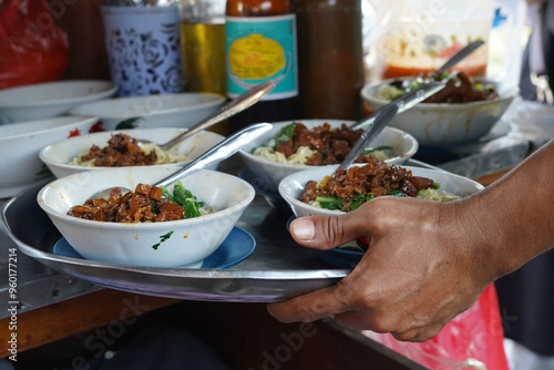 Tukang Mie Ayam or a noodle vendor preparing servings of chicken noodle soup. photo