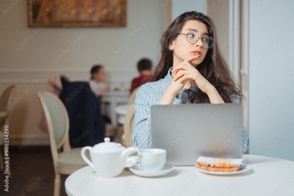 Portrait of a young female freelancer using laptop computer for distance job while sitting in modern coffee shop interior, smart woman working on net-book during morning breakfast in cafe bar Portrait of a young female freelancer using laptop computer for distance job while sitting in modern coffee shop interior, smart woman working on net-book during morning breakfast in cafe bar