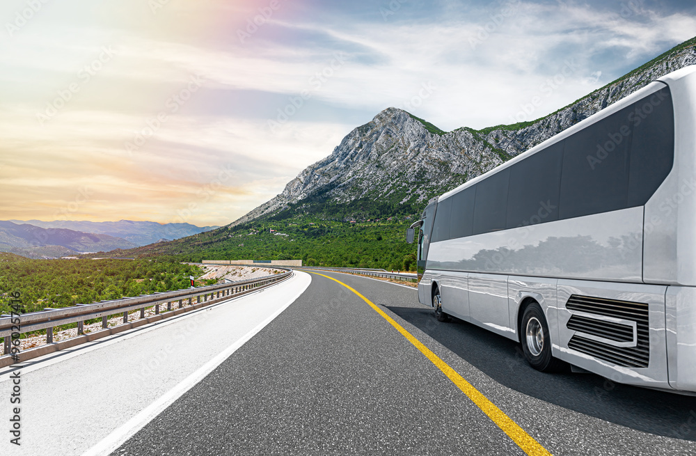 A white tourist bus travels along a picturesque mountain road.