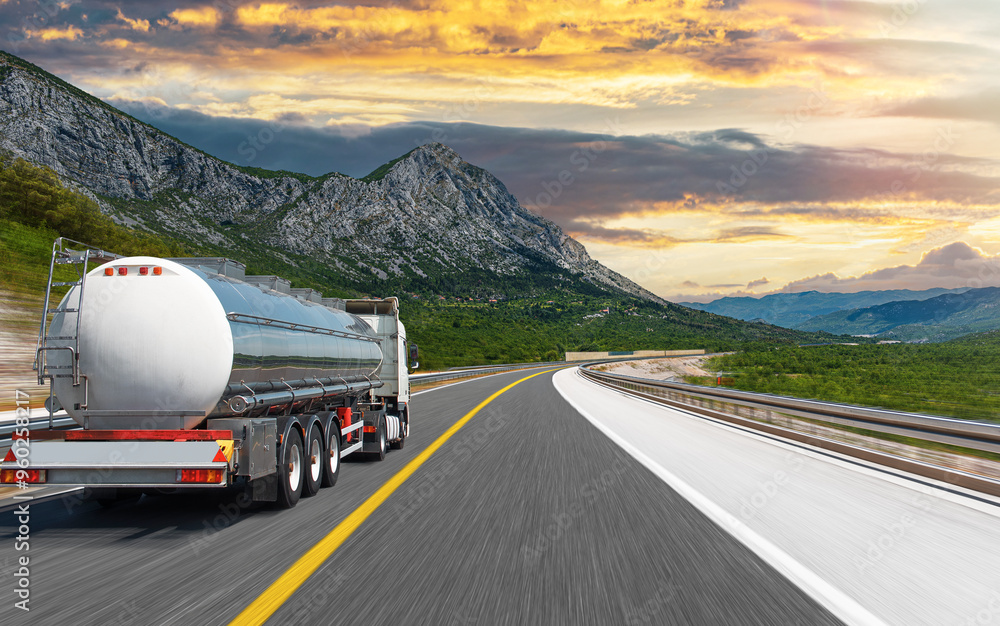 Fuel truck on a picturesque road. A silver tank truck transports fuel.