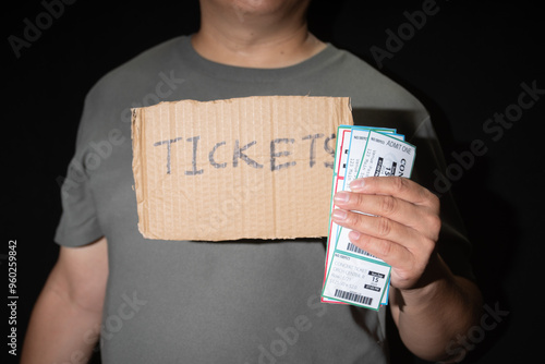 A man displays a sign advertising tickets for sale, a common practice among ticket scalpers