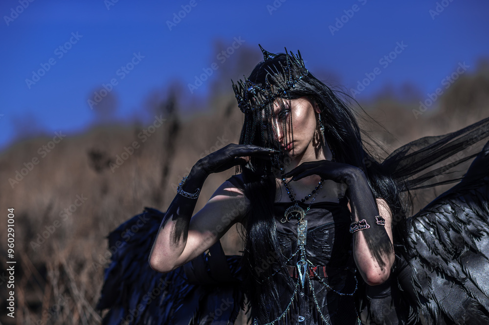 Obraz premium Goddess of death with black wings on a dried field