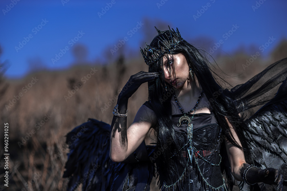 Obraz premium Goddess of death with black wings on a dried field