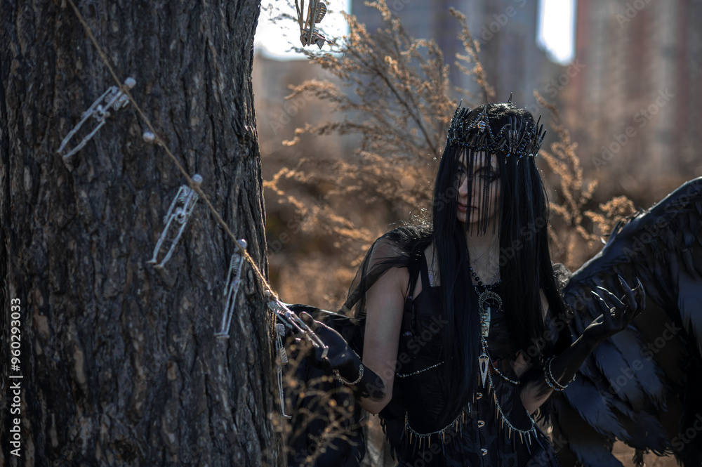 Naklejka premium Goddess of death with black wings on a dried field