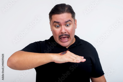 A middle aged man with entomophobia freaks out after seeing a cockroach on his hand. Funny scene with an exaggerated scared reaction. Set against a white background. photo