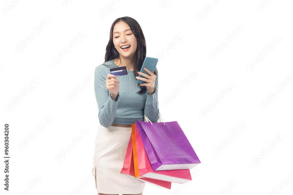 Young asian lady using mobile phone holding credit card carry shopping bags isolated over pastel green background and copy space Smiling young girl purchasing online through phone using credit card Young asian lady using mobile phone holding credit card carry shopping bags isolated over pastel green background and copy space Smiling young girl purchasing online through phone using credit card