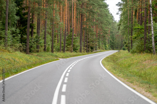 Fototapeta Naklejka Na Ścianę i Meble -  An asphalt road going through a forest in Masuria