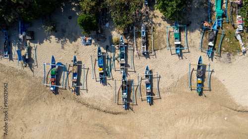 Top-down bird's eye view od aerial drone video flying over juking kano asian type of boats landed on Jimbaran beach at Bali, Denpasar, Indonesia during a sunny day, perspective shot