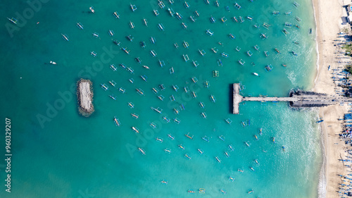 Aerial view of many Indonesian traditional juking boats bobing on turquoise transparent waves near a tropical island of Bali. The concept of an exotic vacation at a seaside resort, perspective shot.	 photo