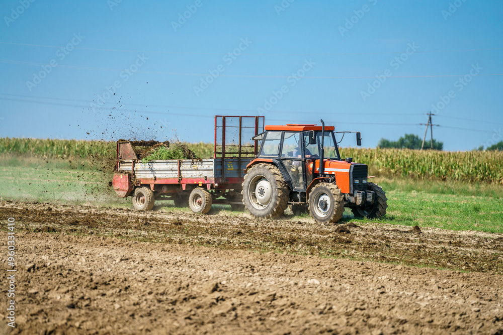 A tractor spreading manure on a field A tractor spreading manure on a field