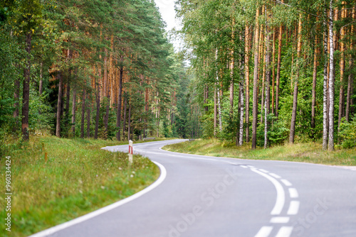 Fototapeta Naklejka Na Ścianę i Meble -  An asphalt road going through a forest in Masuria