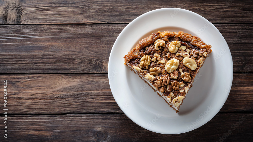 Delicious slice of walnut cake is served on a white plate resting on a rustic wooden table Delicious slice of walnut cake is served on a white plate resting on a rustic wooden table