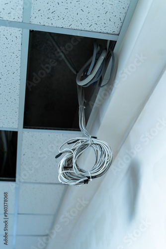 Hanging cables from ceiling tiles in an office renovation project. Cables are suspended from the ceiling tiles during an office renovation photo