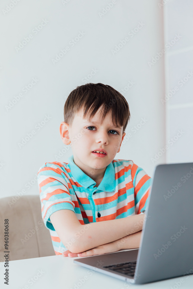 Boy schoolboy sitting at table with laptop online Boy schoolboy sitting at table with laptop online