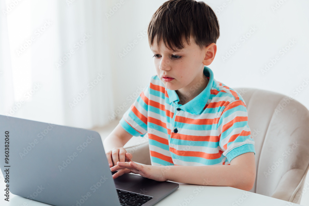 Boy schoolboy sitting at table with laptop online Boy schoolboy sitting at table with laptop online