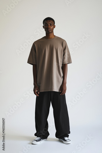 Stylish Male Model Wearing Oversized Clothing and Sneakers on Minimalist White Background