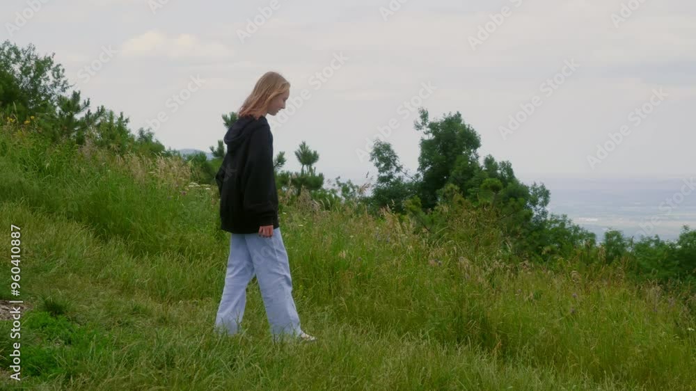Teenage hiker hiking on beautiful grassy hill. Handheld shot of girl wearing casuals enjoying nature. She is having adventure during windy day. Teenage hiker hiking on beautiful grassy hill. Handheld shot of girl wearing casuals enjoying nature. She is having adventure during windy day.