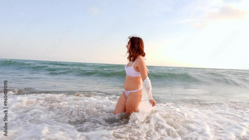 A beautiful young woman in a white swimsuit and veil laughs and enjoys herself in the sea, capturing a moment of joy and carefree fun. A beautiful young woman in a white swimsuit and veil laughs and enjoys herself in the sea, capturing a moment of joy and carefree fun.