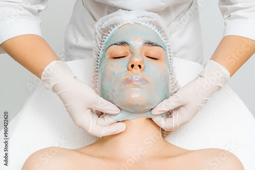 A young woman receives a revitalizing alginate face mask from a skilled cosmetologist in a sleek, modern beauty clinic. Perfect for promoting premium skincare treatments in your ads. photo