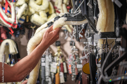 Exploring Equestrian Gear in a Busy Shop, Showcasing a Hand Selecting a Saddle Pad