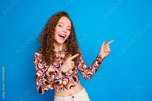 Photo portrait of pretty young girl dancing point empty space wear trendy colorful outfit isolated on blue color background