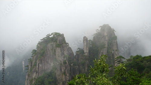Mysterious high stone mountain with clouds in China Huangshan mountains surrounded by fog with some tree leafs