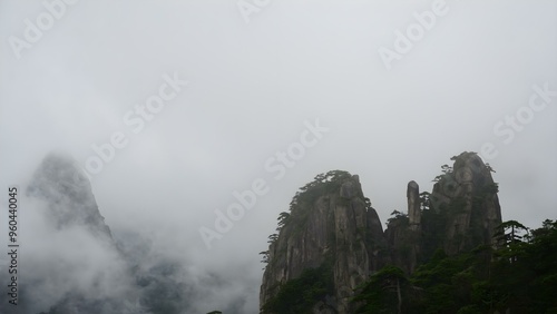 Mysterious high stone hill with clouds in China Huangshan mountains surrounded by fog