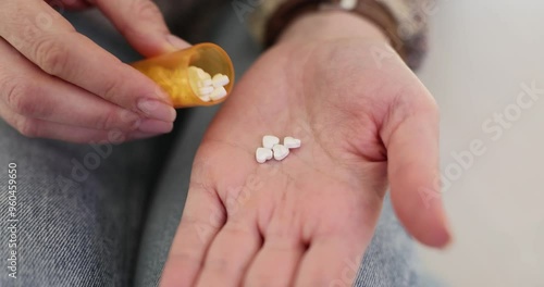 Young woman pours handful of pills on palm for taking. Lady preparing to take prescribed dosage to alleviate symptoms