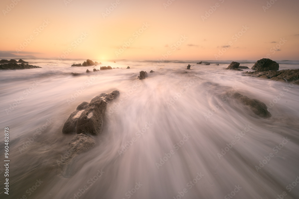 Sunset on Barrika beach, Bizkaia with the waves of the Cantabrian Sea breaking between the rocks Sunset on Barrika beach, Bizkaia with the waves of the Cantabrian Sea breaking between the rocks