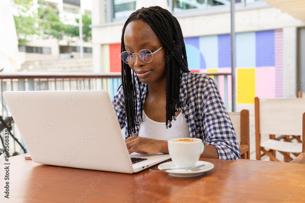 Black woman working on laptop in business district cafe Black woman working on laptop in business district cafe