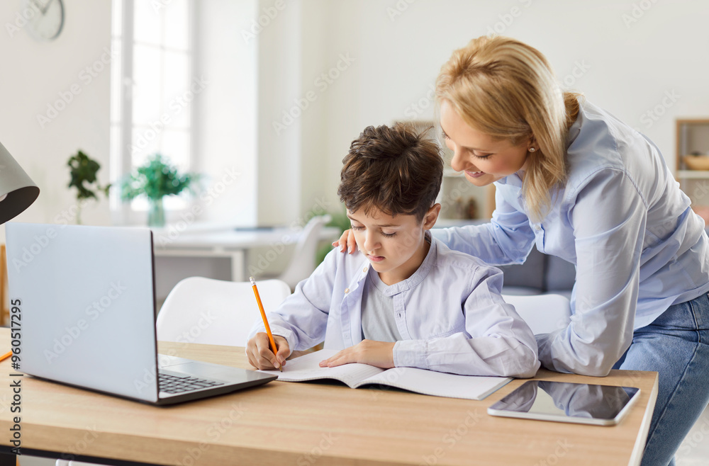 Portrait of a young child boy studying online class on laptop with his cheerful smiling mother at home. Woman help her son with homework during remote lesson. Distance education concept. Portrait of a young child boy studying online class on laptop with his cheerful smiling mother at home. Woman help her son with homework during remote lesson. Distance education concept.